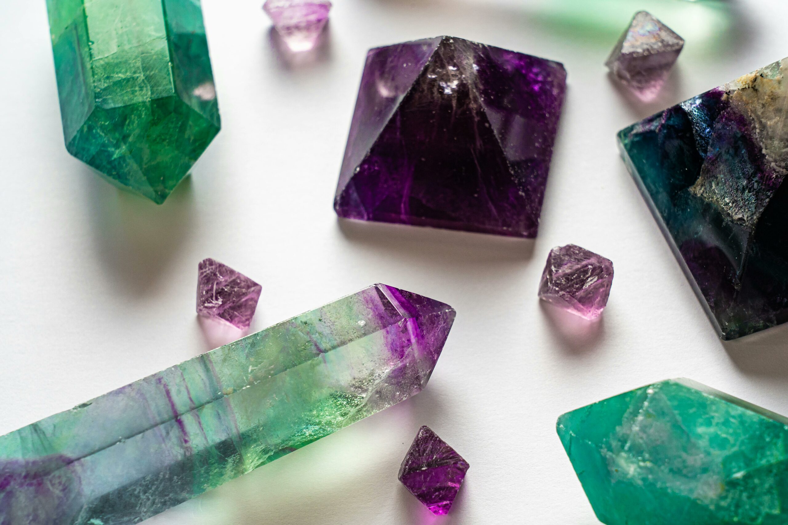 Vibrant close-up of colorful fluorite and amethyst gemstones on a white background.